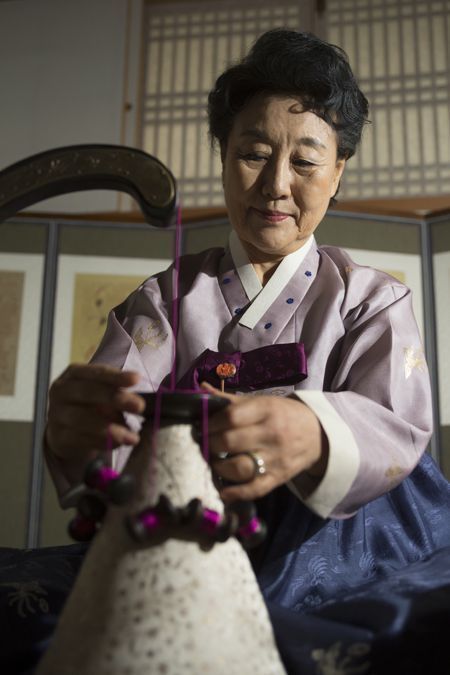 Korean maedeup master Kim Eun-young weaving a dahoe silk cord and tying a traditional decorative knot at her Seoul studio