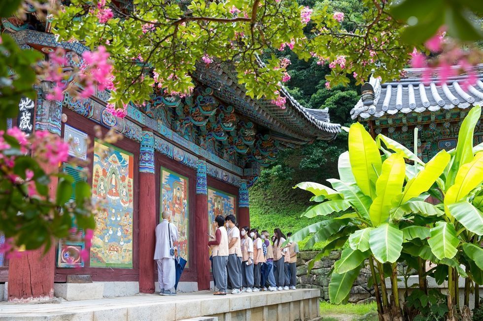 University students follow a Korean Buddhist monk on a guided temple stay tour at Jikji Temple in North Gyeongsang Province during a templestay program