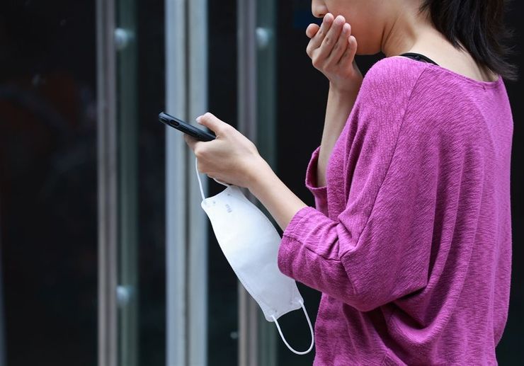 A woman walks with a mask in her hand on a street in Jung District, Seoul, Friday. The outdoor mask mandate, which went into effect from April 2021, will be fully lifted starting Monday. Yonhap