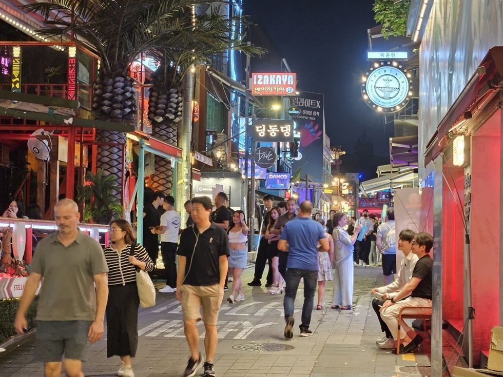 A bustling Itaewon street in Seoul filled with pedestrians, neon signs, and international restaurants at night
